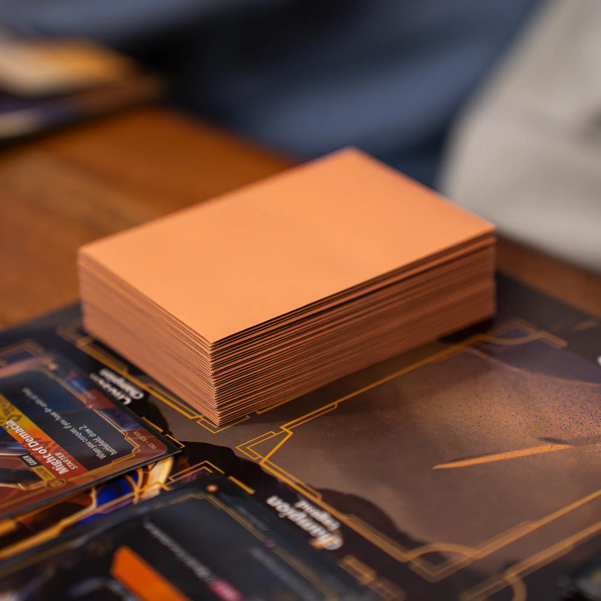 deck of peach matte textured dual reef sleeves with black inside and clear front for standard size tcg trading cards placed on playmat